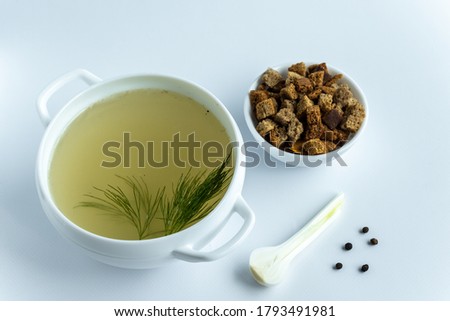 Homemade meat broth in a tureen with dill. Croutons and spices. on a white background. Healthy food concept. Paleo diet.