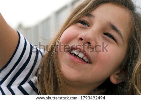 CLOSE UP PORTRAIT OF A HAPPY GIRL HAVING FUN AND SMILING WHILE LOOKING AT THE SKY.

