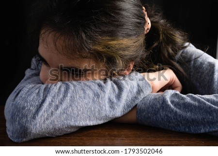 closeup of female teenager sneezing into the inside of the elbow with dark background