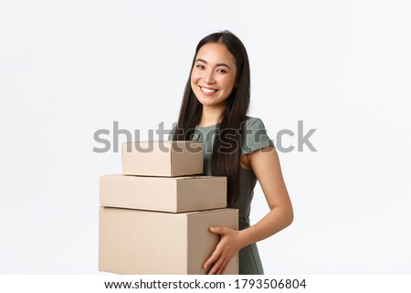 Small business owners, startup and work from home concept. Smiling young store manager, asian businesswoman collect packages, packing orders in boxes and carry them to delivery company