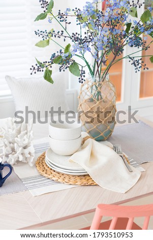 Home dining room interior, table with white tablecloth and flowers in vase.
