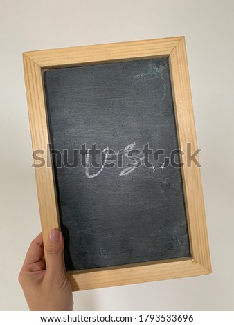 hand holding small chalkboard with writing