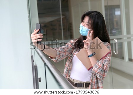Woman wearing face mask taking self portrait with her camera phone