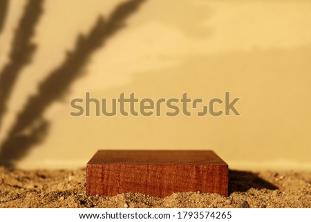 Wooden square pedestal on sand. Beige background, plant shadow. Monochrome brown template for banner, poster. Mockup for natural product, eco cosmetic packaging. Sultry mood. Hard sunlight trend Royalty-Free Stock Photo #1793574265