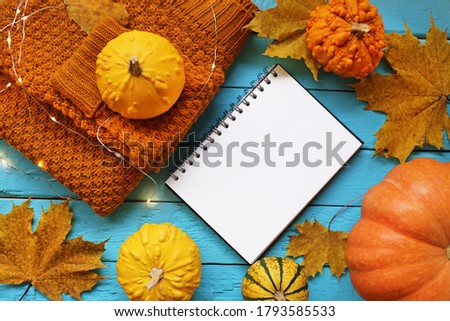 Thanksgiving day. Autumn Mock up.Autumn flat lay. Blank notebook, sweater, pumpkin yellow set and glowing garlands on blue wooden background..autumn to-do list.Painting mock-up.
