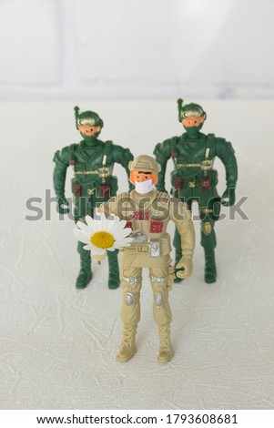 Three soldier in medical mask with chamomile flower in the hand.