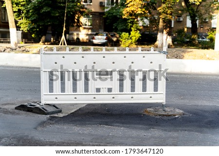 White safety barrier on the road. Road signs denoting road repairs
