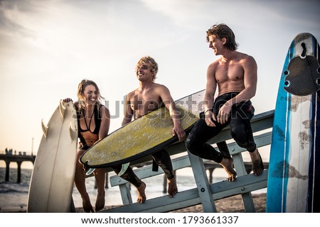 Three surfers relaxing on the beach after sport Royalty-Free Stock Photo #1793661337
