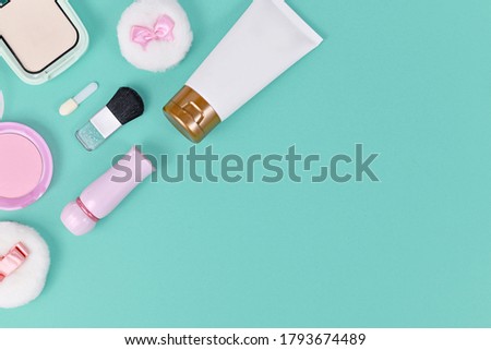 Flat lay with makeup beauty products like lipstick, powder or foundation in corner of mint green background with copy space on side