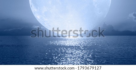 Night sky with Blue moon in the clouds on the fore ground calm blue sea "Elements of this image furnished by NASA