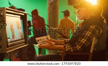 Director Looks at Display in Anger, Swears while Shooting Blockbuster Movie. Green Screen Scene with Actors Wearing Costumes. On Film Studio Set Professional Crew Doing High Budget Movie