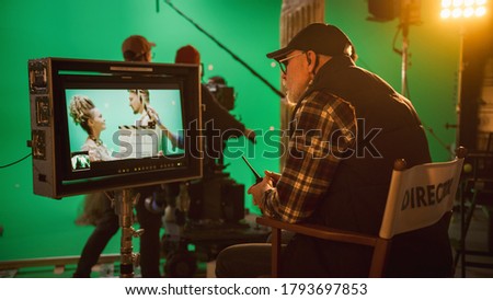 Director Looks at Display Controls Shooting Period Drama Movie. Green Screen CGI Scene with Actors Wearing Renaissance Costumes. Big Film Studio Professional Crew Shooting High Budget Movie.