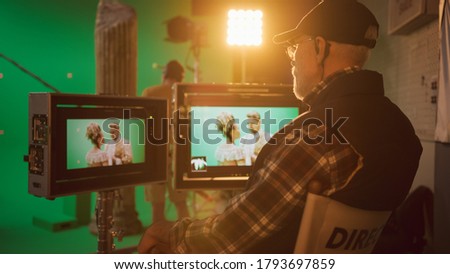 Director Looks at Display Controls Shooting Period Drama Movie. Green Screen CGI Scene with Actors Wearing Renaissance Costumes. Big Film Studio Professional Crew Shooting High Budget Movie