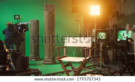 Film Studio Set with Focus on Empty Director's Chair. On the Studio Film Set with High End Equipment Professional Crew Shooting High Budget Movie