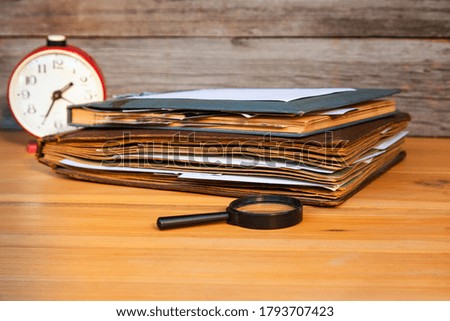 Clock and albums with old family photographs on a light wooden table.