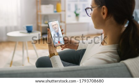 Young Girl Sick at Home Using Smartphone to Talk to Her Doctor via Video Conference Medical App. Woman Checks Possible Symptoms with Professional Physician, Using Online Video Chat Application Royalty-Free Stock Photo #1793708680