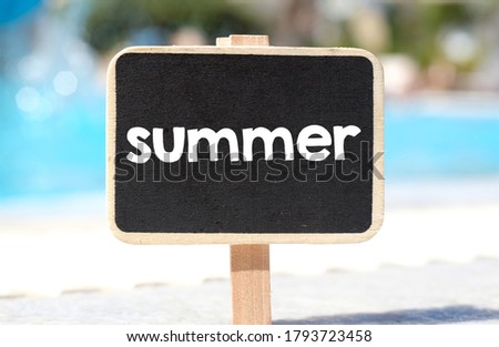 The word Summer written on a chalkboard in the background of sunny weather in a hotel resort.