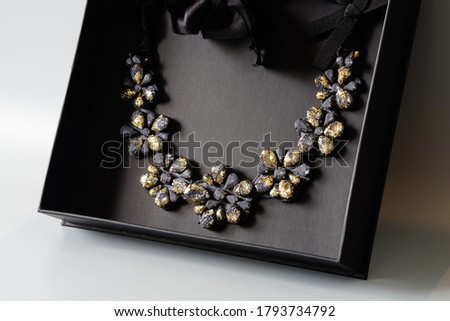 floral necklace, woman jewelry in black box on a gray background, goth, dark fashion. black and gold necklace,