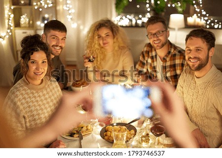 holidays, celebration and people concept - happy friends photographing at home christmas dinner party