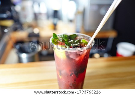 Mojito cocktail or soda drink with lime,raspberry and mint on table in bar.Blurred image,selective focus