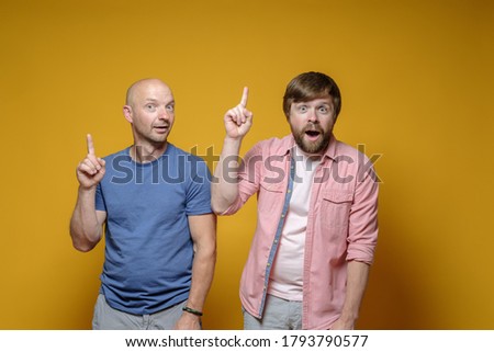 Great idea. Two funny men raise their index fingers up and look at the camera with joy, intrigue. 
