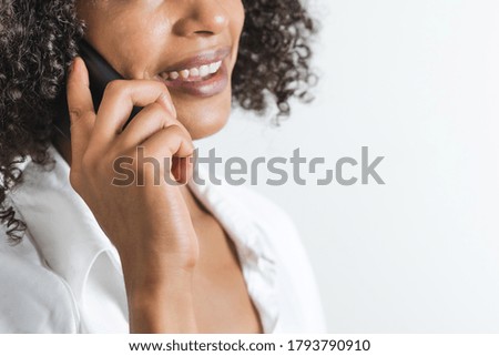 close-up of a phone hold by a young smiling afro woman with copy space on the right