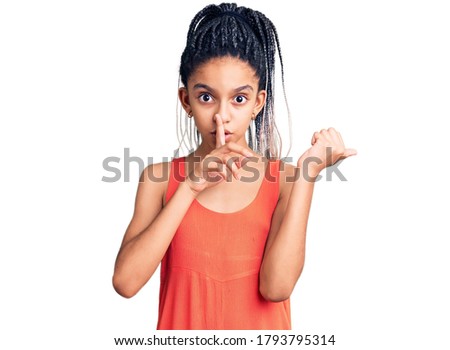 Cute african american girl wearing casual clothes asking to be quiet with finger on lips pointing with hand to the side. silence and secret concept. 