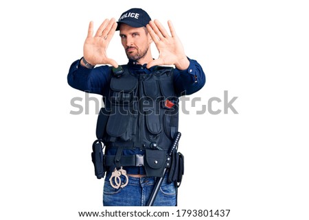 Young handsome man wearing police uniform doing frame using hands palms and fingers, camera perspective 
