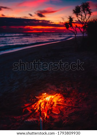 Bonfire on beach with waves and bright sunset or sunrise in Bali.