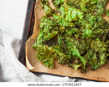 Green Kale Chips with salt on oven-tray. Homemade healthy snack for low carb, keto, low calorie diet. Gray cement background. Ready-to-eat kale chips, copy space for text Royalty-Free Stock Photo #1793811847