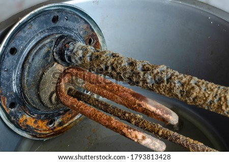 Water heater flange with anode, temperature sensor and electric heating element. Closeup of an old water heater detail. Service and repair. Selective focus. Royalty-Free Stock Photo #1793813428