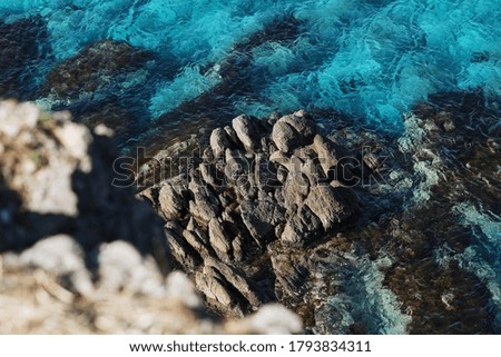 Beautiful stony sea beach in Russia. Rich transparent blue sea is an excellent background for design. The photo with rocks and wild seascape for recreation and tourism.