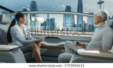 Beautiful Female and Senior Man are Having a Conversation in a Driverless Autonomous Vehicle. Futuristic Self-Driving Van is Moving on a Public Highway in a Modern City with Glass Skyscrapers. Royalty-Free Stock Photo #1793836633