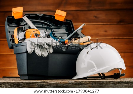 Open plastic tool kit box with construction safety helmet and various hand tools. Royalty-Free Stock Photo #1793841277