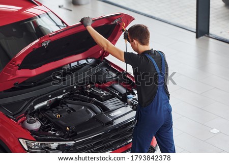 Top view of male worker in uniform that repairs red automobile. Royalty-Free Stock Photo #1793842378
