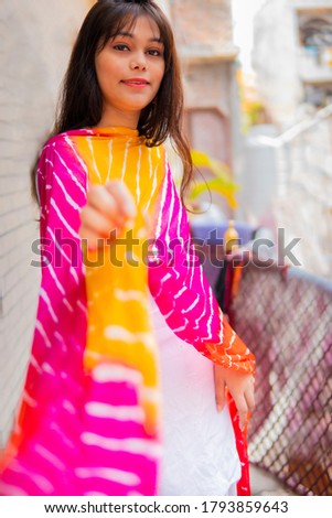 Beautiful happy Indian girl in traditional Indian dress (Salwar Kameez, dupatta) and enjoying fresh air in outdoor and looking at the camera with toothy smile. 
