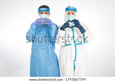 Woman doctor wearing PPE to fight the coronavirus, holding in her hands a colonial-era explorer's hat, on white background. Warrior. COVID medicine concept