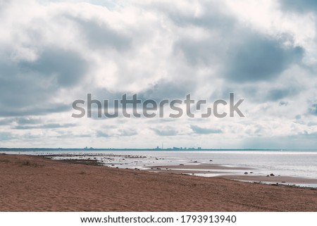 Deserted beach with cloudy sky and city on the horizon