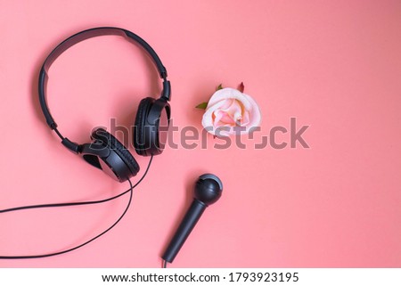Headphones, microphone and roses on a pink background. Singing and music lessons concept.