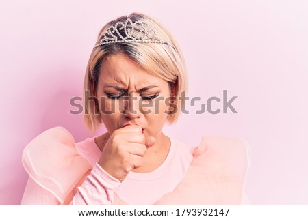 Beautiful blonde plus size woman wearing pincess tiara with diamonds over pink background feeling unwell and coughing as symptom for cold or bronchitis. Health care concept.