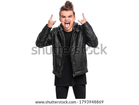 Crazy teen boy with spooking make-up making Rock Gesture, isolated on white background. Teenager in style of punk goth dressed in black screaming and shouting and doing heavy metal rock sign.