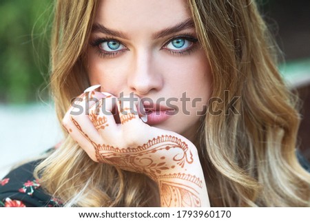 Beautiful girl with a painting of mehendi on her hands.  Mehndi, application of henna as skin decoration. Woman with traditional mehndi henna ornament
