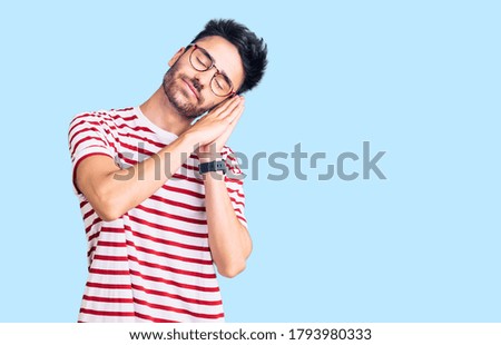 Young hispanic man wearing casual clothes sleeping tired dreaming and posing with hands together while smiling with closed eyes. 