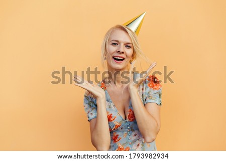Attractive positive woman celebrates birthday, shocked with unexpected news, enjoys party. isolated orange pastel background. Time for fun and entertainment
