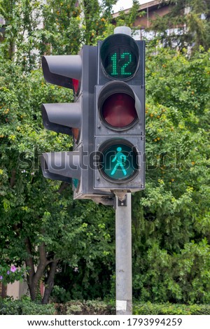 An electric traffic light and a sign for another 12 seconds for pedestrians to cross the street.