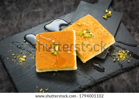 Traditional turkish dessert as known Kunefe or Kunafah or Kunafeh or Kunafa Kadayif. This is middle eastern dessert made pistachio and cream on Black background. Royalty-Free Stock Photo #1794001102