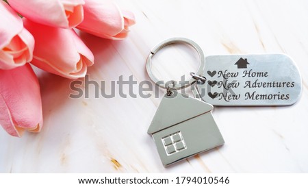House keychain on wooden background, welcome buyer to new home. Concept of greeting customers for real estate agent.