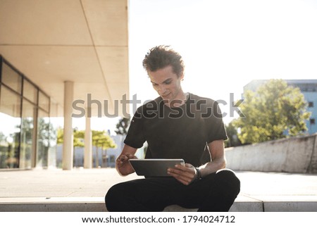 Handsome young entrepreneur doing business on digital tablet outside office. High quality photo