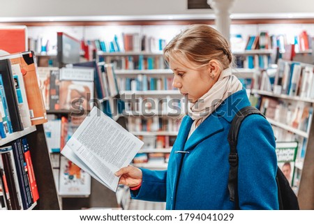 A woman leafing through a book in a store. Side view. The concept of buying books and preparing for school