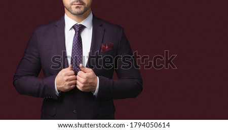 Sharp dressed man in jacket and tie isolated on dark red background. Picture for advertising a men's clothing store. A symbol of success and masculinity